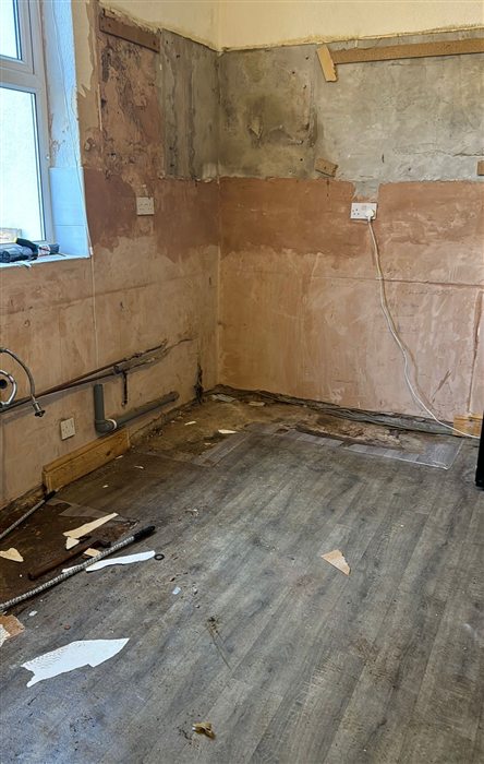 Kitchen stripped to bare plaster with old flooring