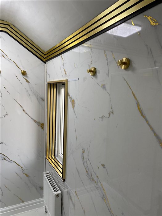 Shower room with brass window trim and marble-effect panels