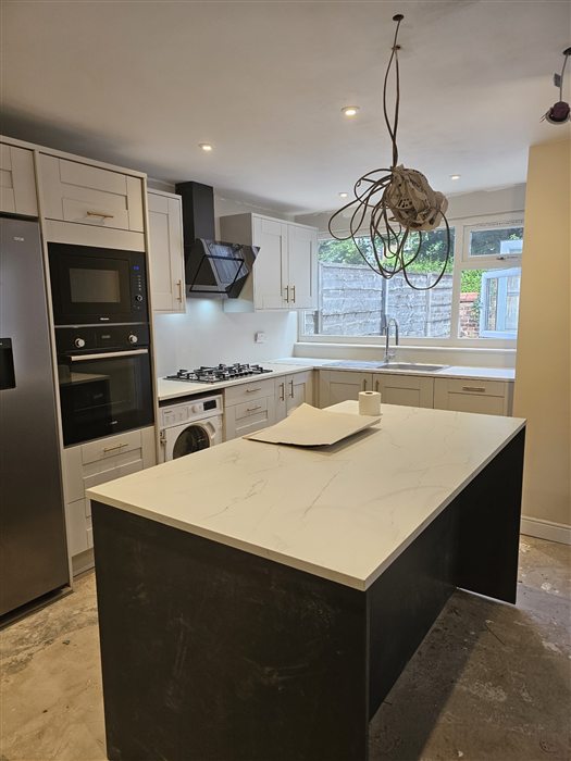Kitchen with a dark island and white quartz-effect worktop