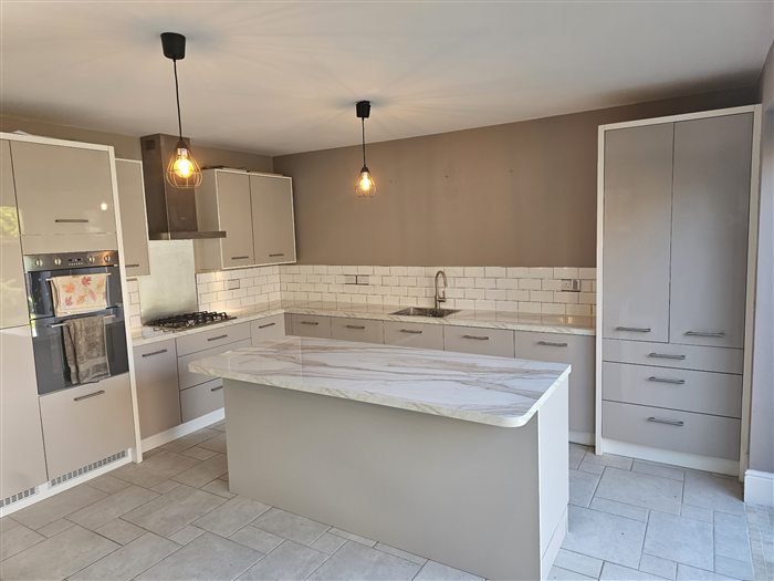 Kitchen with marble-effect island, pendant lights and tall larder units