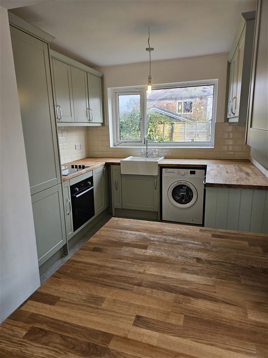 Sage shaker kitchen with oak worktops and a butler sink