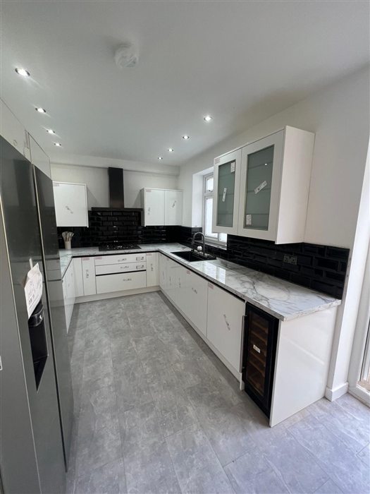 White gloss L-shaped kitchen with black worktop
