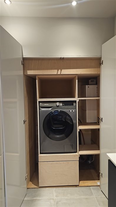 Utility cupboard housing a washing machine with shelves